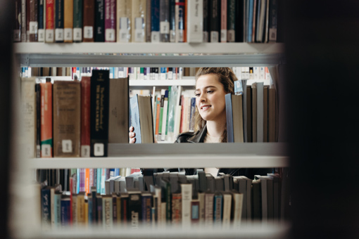 Woman selecting a book from a book shelf in the Canberra Library.